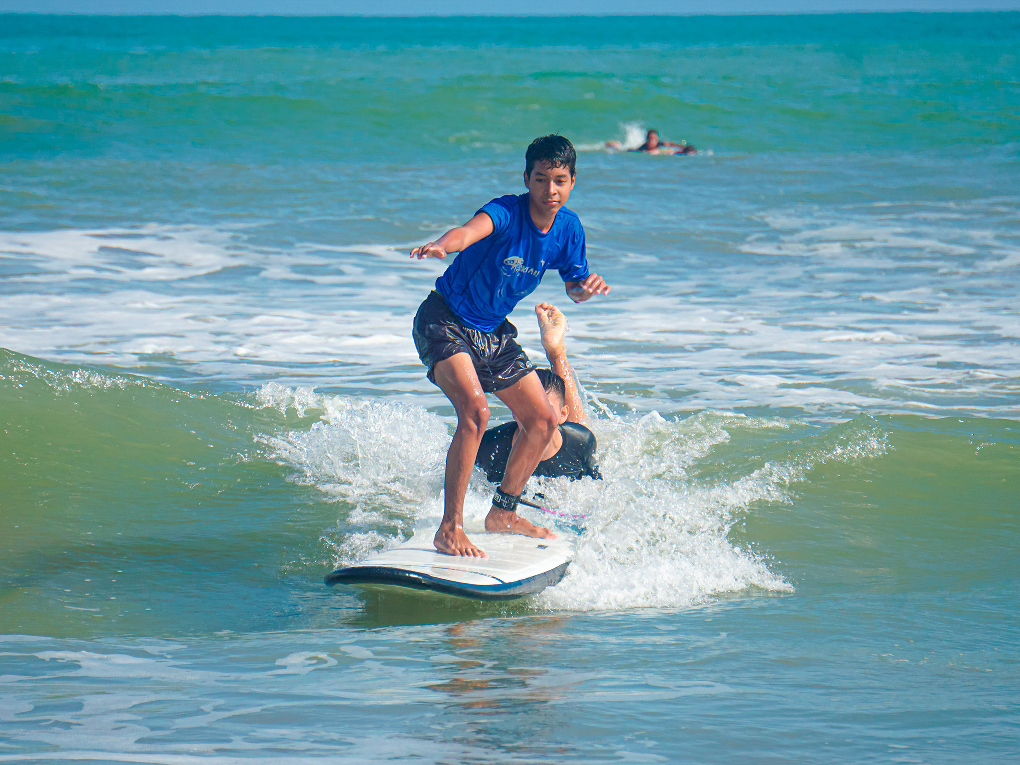Instructor dirigiendo el calentamiento junto al mar con alumnos y tablas